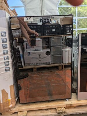 un homme debout à côté d'un micro-ondes posé sur une palette
