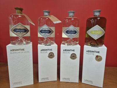 trois bouteilles d'absinthe et une boîte d'absinthe posées sur une table