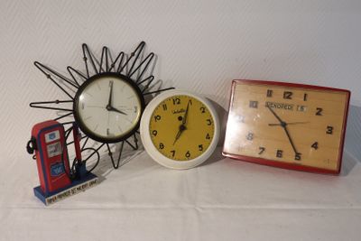 three different clocks and a telephone on a table