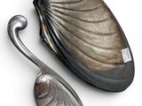 two silver spoons and a spoon rest on a white surface