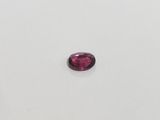 a pink tourmaline stone on a white surface