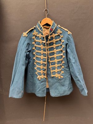 une vieille veste militaire bleue suspendue à un cintre accroché au mur