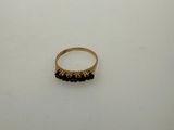 a gold ring with black stones sits on a white surface