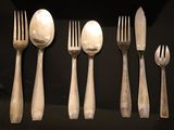 five forks and five spoons on a black table