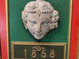 a picture of a plaque of a woman ' s face on a green and red frame