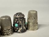 three silver thimbles are lined up on a white surface