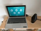 un ordinateur portable posé sur un bureau en bois, avec un haut-parleur