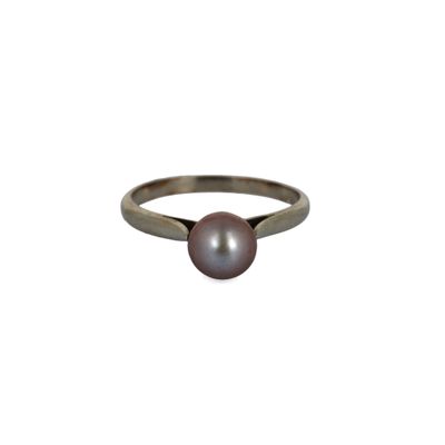 un gros plan d'une bague ornée d'une perle sur fond blanc