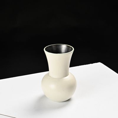 a white vase sitting on top of a piece of paper