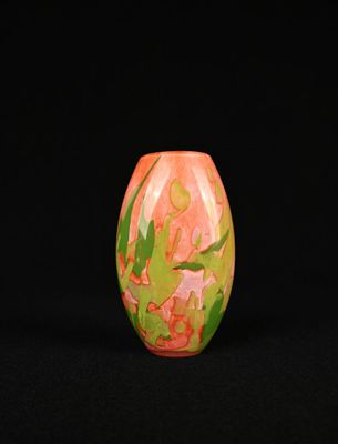 un vase orange et vert posé sur une surface noire