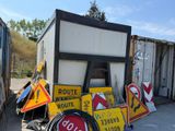 a pile of road signs and signs on the side of the road