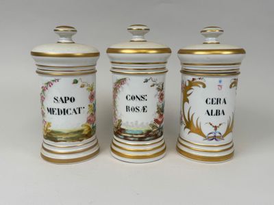 three white and gold canisters with different designs on them