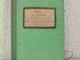 un livre vert posé sur une table, avec un mur blanc en arrière-plan