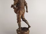 bronze statue of a man with a hat and boots on top of a pedestal