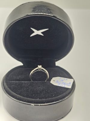 une bague en argent dans un écrin noir posé sur une table blanche