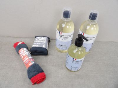 trois bouteilles de liquide, une serviette et une serviette posée sur un canapé