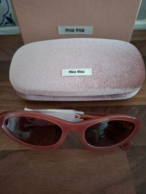 une paire de lunettes de soleil roses posée sur une table en bois
