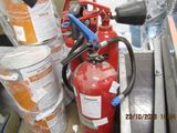 a red fire extinguisor sitting next to a bucket of oranges
