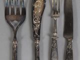 four forks, a knife, and a spoon are lined up on a table