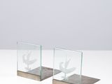 une paire de serre-livres en verre et en bois posés sur une surface blanche