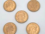 six gold sovereigns are arranged in a row on a white surface