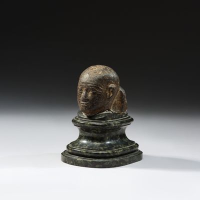 un gros plan sur une statue représentant une tête posée sur un socle