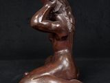 a bronze statue of a woman sitting on a black background