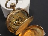 une montre de poche en or posée sur une surface noire