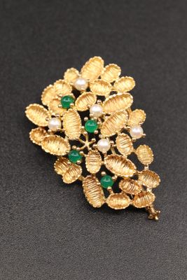 un gros plan d'une broche ornée de perles et de pierres vertes