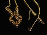 gold necklace with a cross and a chain on a black background