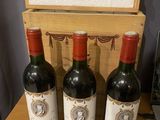 three bottles of red wine sit on a table next to a wooden box
