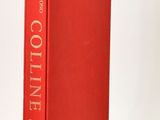 the red book is sitting on a white surface next to a white vase