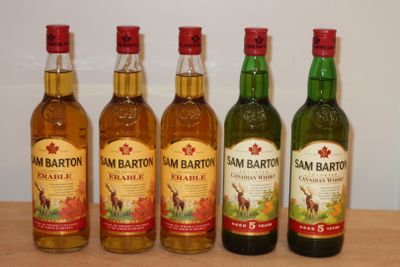 Quatre bouteilles de whisky canadien sont alignées sur une table