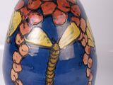 un vase bleu sur lequel est peinte une libellule