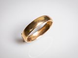 gros plan d'une bague en or sur une surface blanche