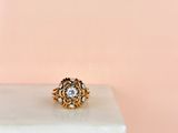 a close up of a gold and diamond ring on a marble block