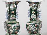 pair of green vases with floral designs on stands against a white background