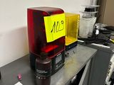 un mixeur rouge posé sur un bureau, à côté d'un panneau jaune