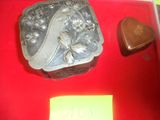 une boîte en argent sur laquelle figure le portrait d'une femme, posée sur une table rouge