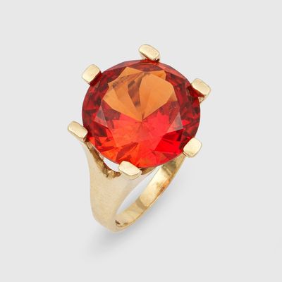 une bague en or ornée d'une grosse pierre rouge au centre