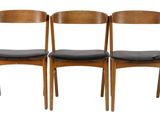 four wooden chairs with black leather seats on a white background
