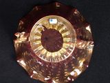 a red glass plate with a gold rim on a black surface