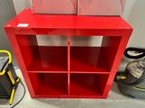 une bibliothèque rouge sur laquelle sont posées deux boîtes