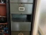 a tall metal filing cabinet in a room with a lot of clutter