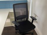 a black office chair sitting in front of a white desk