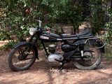 une moto noire garée sur la terre battue