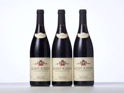 trois bouteilles de vin sont posées sur une table devant un fond blanc