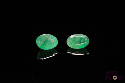 a pair of emerald earrings on a black surface