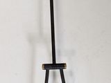 a black and gold clock on a stand on a white wall
