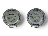 two blue and white plates with birds on them on a white surface